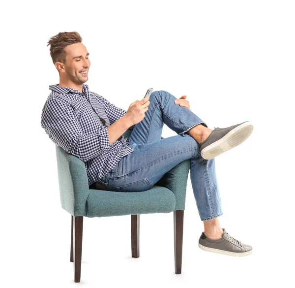 Hombre guapo con teléfono móvil sentado en sillón sobre fondo blanco — Foto de Stock