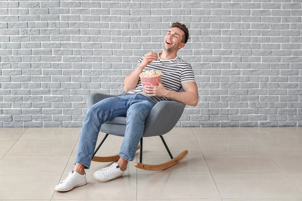 Homem feliz assistindo filme enquanto sentado em poltrona perto da parede cinza — Fotografia de Stock