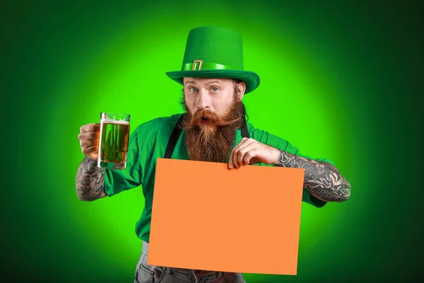 Bearded man with blank poster and glass of beer on dark background. St. Patrick's Day celebration — Stock Photo, Image