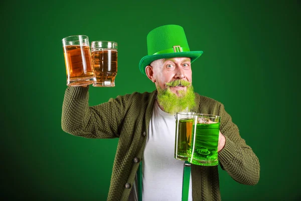 Funny mature man with glasses of beer on dark background. St. Patrick\'s Day celebration
