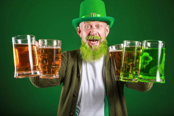 Funny mature man with glasses of beer on dark background. St. Patrick\'s Day celebration