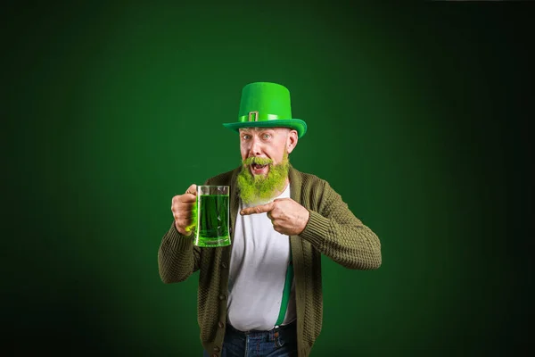 Funny mature man with glass of beer on dark background. St. Patrick\'s Day celebration