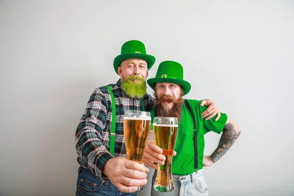 Bearded men with glasses of beer on light background. St. Patrick's Day celebration — Stock Photo, Image