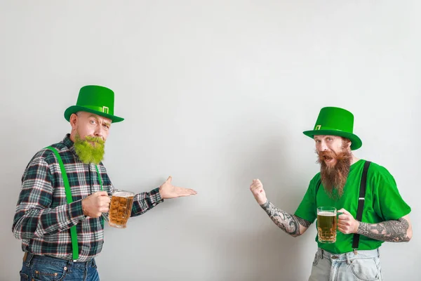Bearded men with glasses of beer showing something on light background. St. Patrick's Day celebration — Stock Photo, Image