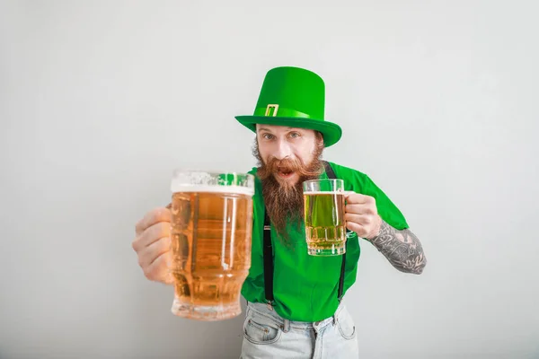 Uomo barbuto con bicchieri di birra su sfondo chiaro. Festa di San Patrizio — Foto Stock