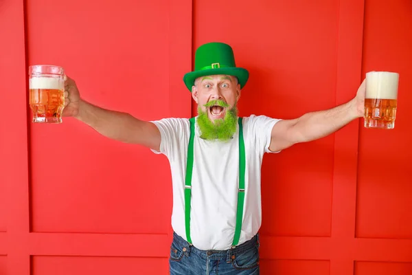 Lustiger älterer Mann mit Biergläsern auf farbigem Hintergrund. St. Patrick 's Day Feier — Stockfoto