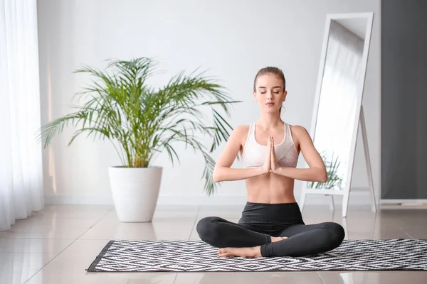 Beautiful young woman practicing yoga at home — Stock Photo, Image