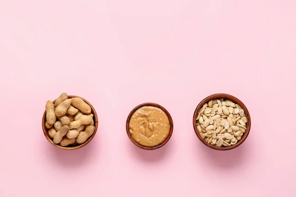 Bowls with peanut butter and nuts on color background — Stock Photo, Image