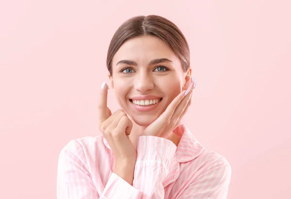 Hermosa mujer joven aplicando crema en su cara contra el fondo de color — Foto de Stock