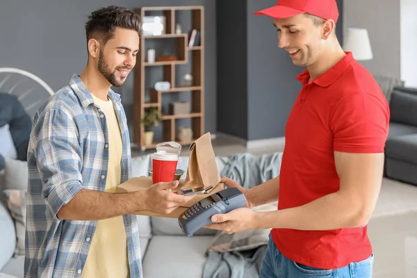 Man paying courier for food delivery via terminal — 스톡 사진