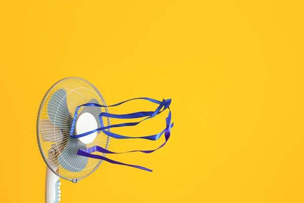 Electric fan with fluttering ribbons on color background — ストック写真