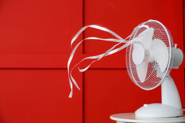 Ventilador eléctrico con cintas aleteo cerca de la pared de color —  Fotos de Stock