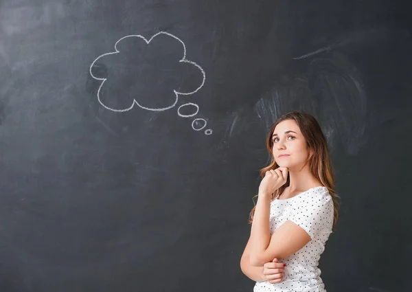 Thoughtful young woman with blank speech bubble on dark background — 스톡 사진