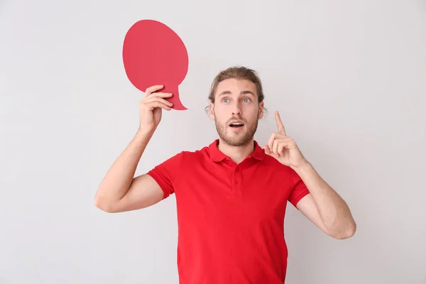 Young man with blank speech bubble and raised index finger on grey background — Stock Photo, Image