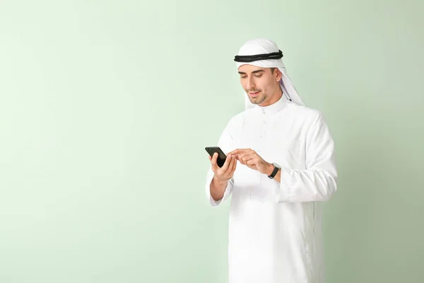 Красивый арабский мужчина с мобильным телефоном на цветном фоне — стоковое фото