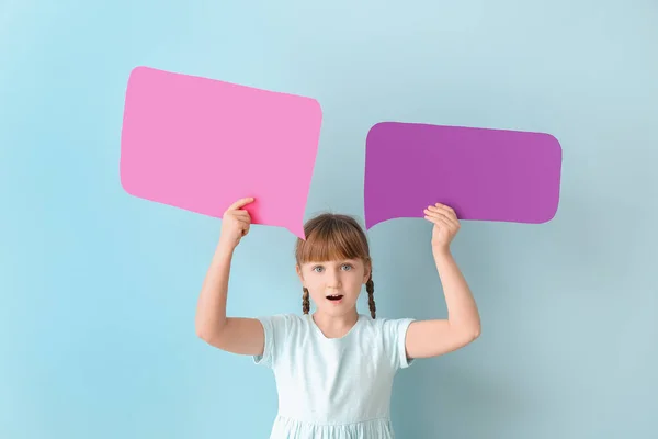 Surprised little girl with blank speech bubbles on color background — Stock Photo, Image