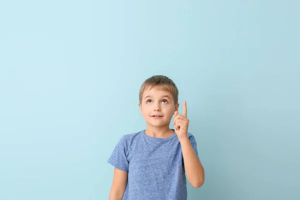 Cute little boy with raised index finger on color background — Stock Photo, Image