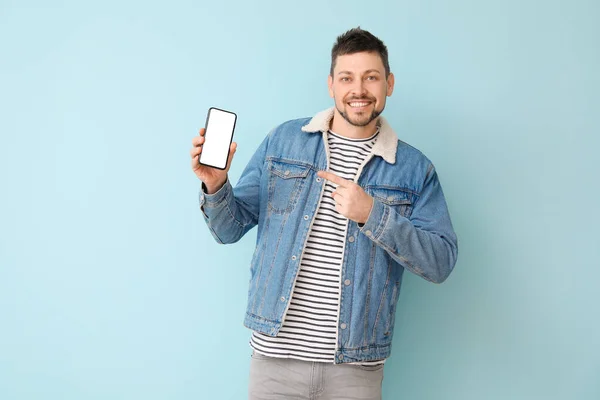 Happy man with mobile phone on color background