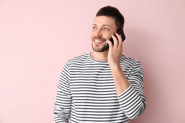 Happy man talking by mobile phone on color background — Stock Photo, Image