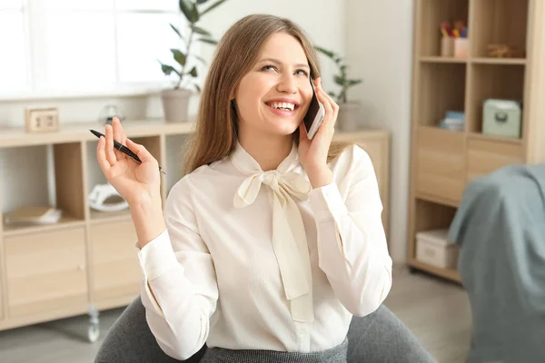 Young businesswoman talking by mobile phone indoors — Stock Photo, Image