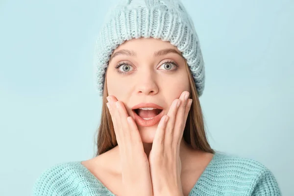 Verrast vrouw in de winter kleding op kleur achtergrond — Stockfoto
