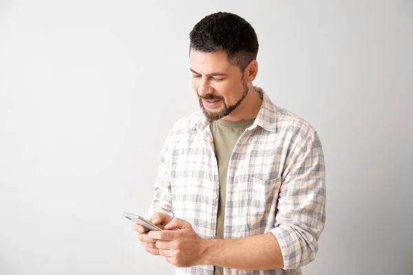 Hombre maduro con teléfono móvil sobre fondo claro — Foto de Stock