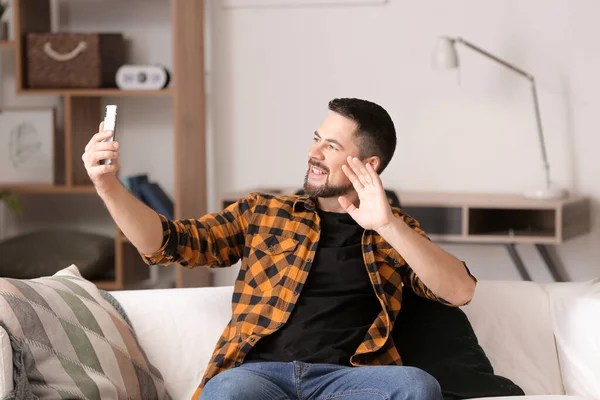 Homem maduro com telefone celular tirando selfie em casa — Fotografia de Stock