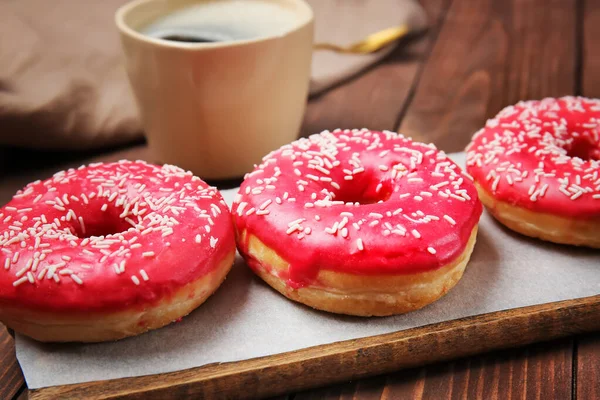 Sweet tasty donuts and cup of coffee on wooden background — Stock Photo, Image