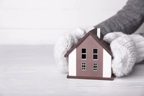 Kobieta w rękawiczkach i modelu domu na białym tle. Koncepcja zimowa — Zdjęcie stockowe