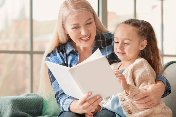 Klein meisje en grootmoeder lezen samen boek thuis — Stockfoto