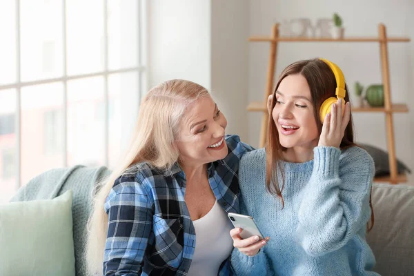 年轻妇女和母亲在家里一起听音乐 — 图库照片