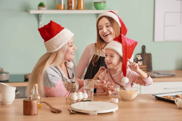 Mujer joven con su hija y su madre cocinando galletas de Navidad en casa — Foto de Stock