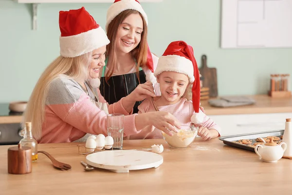 Ung kvinna med sin lilla dotter och mor matlagning julkakor hemma — Stockfoto