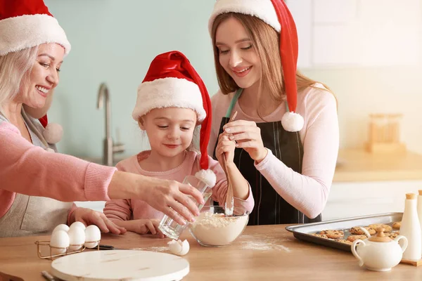 Young woman with her little daughter and mother cooking Christmas cookies at home — Stock Photo, Image