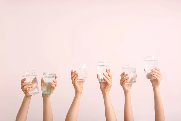 Female hands with glasses of water on color background — Stock Photo, Image