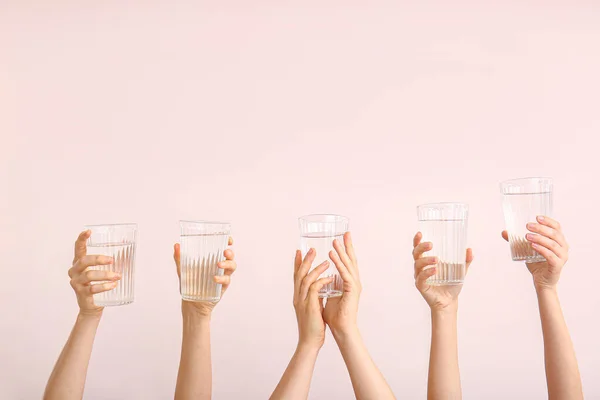 Female hands with glasses of water on color background — Stock Photo, Image