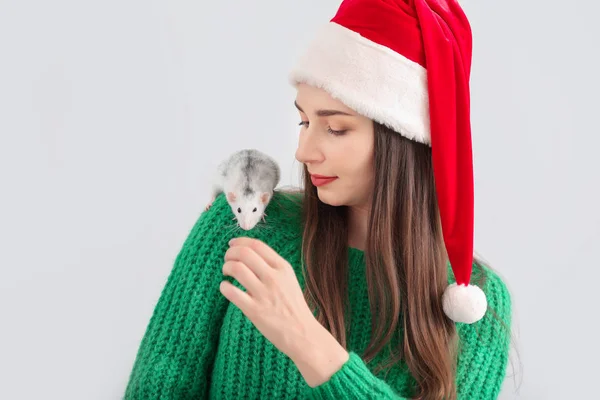 Mladá žena v klobouku Santa Claus a s roztomilou krysou na bílém pozadí — Stock fotografie