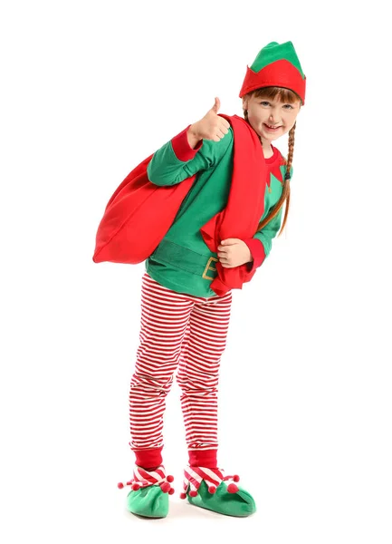 Liten flicka i kostym nisse och med Santa Claus väska visar tummen upp gest på vit bakgrund — Stockfoto