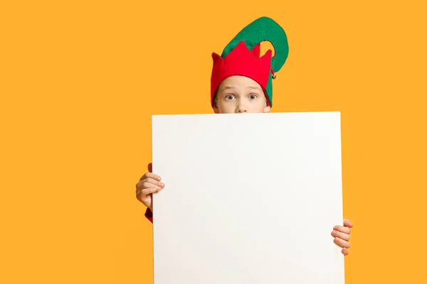 Ragazzo sorpreso in costume da elfo e con poster in bianco su sfondo a colori — Foto Stock