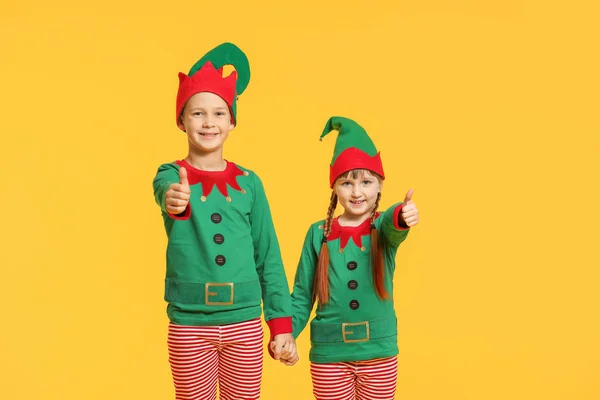 Kleine Kinder im Elfenkostüm zeigen Daumen-hoch-Geste auf farbigem Hintergrund — Stockfoto