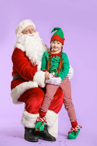 Weihnachtsmann und kleines Elfenkind auf farbigem Hintergrund — Stockfoto
