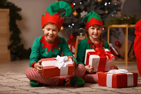 Niños pequeños disfrazados de elfo y con regalos en la habitación decorada para Navidad — Foto de Stock