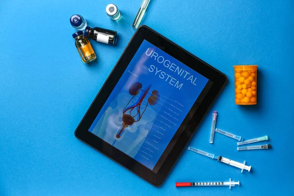 Tablet computer with picture of urogenital system on screen and medicines on color background — Stock Photo, Image