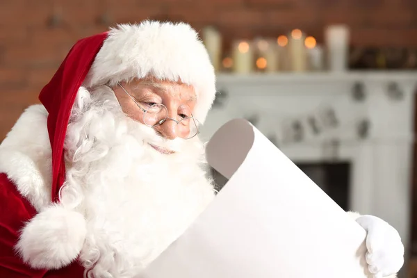 Weihnachtsmann liest Wunschzettel in weihnachtlich dekoriertem Zimmer — Stockfoto