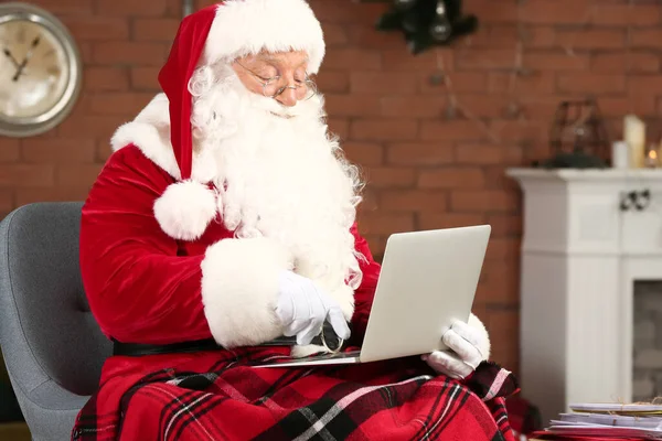 Święty Mikołaj z laptopem w pokoju udekorowane na Boże Narodzenie — Zdjęcie stockowe