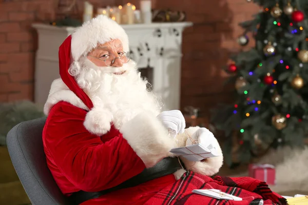 Santa Claus with letters in room decorated for Christmas — Stock Photo, Image