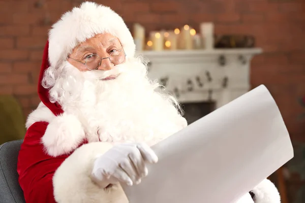 Santa Claus reading wish list in room decorated for Christmas — Stock Photo, Image