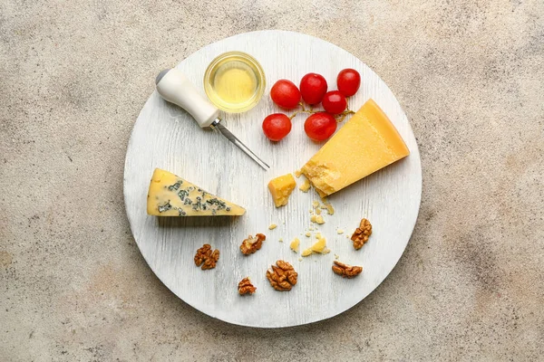 Board with assortment of fresh cheeses and honey on grey background — Stock Photo, Image