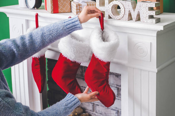 Woman hanging socks on fireplace at home