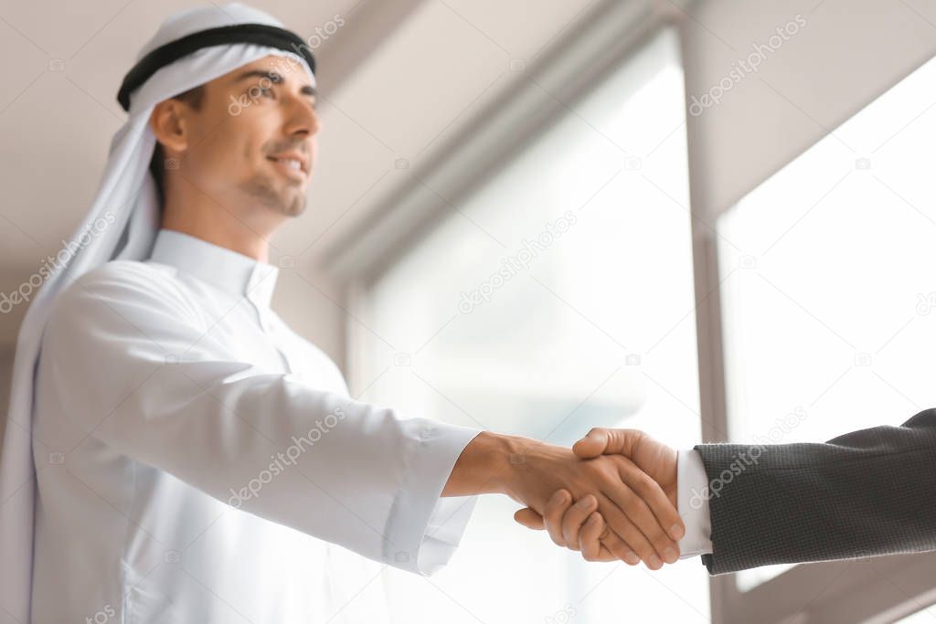 Arab businessmen shaking hands in office